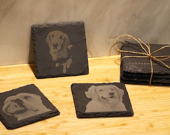 Könnte beinhalten: Vier schwarze Schieferuntersetzer mit eingegrabenen Bildern von Hunden. Die Untersetzer sind auf einer Holzoberfläche angeordnet. Ein Untersetzer hat den Text "PORTUGUESE" eingegraben.