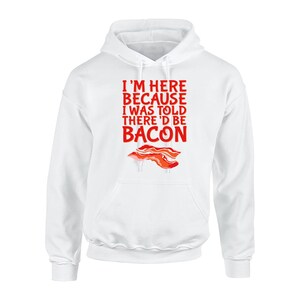May include: White hoodie featuring the red text "I'M HERE BECAUSE I WAS TOLD THERE'D BE BACON". A bacon graphic is below the text. The sweatshirt has a front pocket and a drawstring hood.