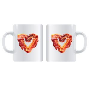 May include: Two white coffee mugs, each featuring a heart shape made from crispy bacon. The bacon is a mix of red and brown, contrasting against the white mugs. The mugs have a standard handle.