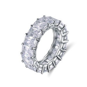 May include: A silver ring with a row of clear, square-shaped stones set in a continuous band.
