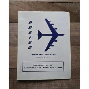 May include: A white manual with blue text and a blue airplane graphic. The cover reads BOEING AIRPLANE COMPANY WICHITA DIVISION and RECLAMATION OF HARDWARE AND ROTO BIN ITEMS. The manual features a vertical orientation with a clean, printed design.
