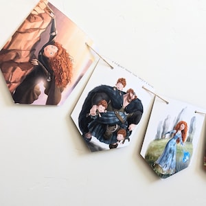 May include: A decorative banner featuring illustrations of characters from the animated film "Brave." The banner includes images of Merida, her family, and scenes from the movie. The pennants are strung together with twine.