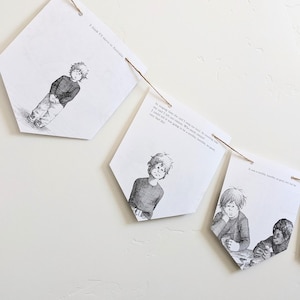 Puede incluir: Una guirnalda de banderines de papel ilustrados, ensartados en una cuerda. Cada banderín presenta un dibujo en blanco y negro de un niño y texto de un libro. Los banderines tienen forma de diamante y cuelgan de una pared blanca.