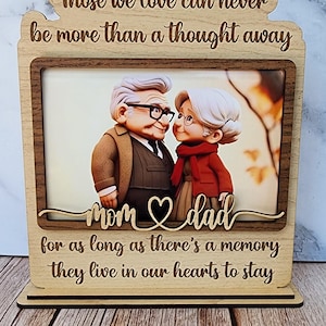 May include: Wooden photo frame with a picture of an elderly couple. The frame has the text "Those we love can never be more than a thought away" and "Mom & Dad for as long as there's a memory they live in our hearts to stay."