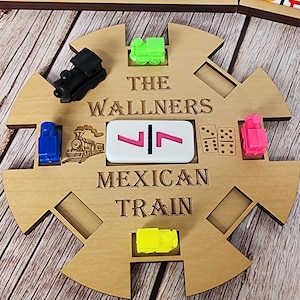 May include: Wooden Mexican Train dominoes game set with a decorative wooden centerpiece, colorful train markers, and dominoes. The centerpiece has the text "THE WALLNERS MEXICAN TRAIN".