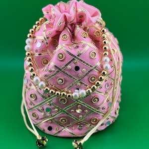 May include: A pink drawstring bag with gold and silver embroidery and a pearl and gold bead trim.