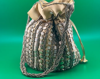May include: A beige drawstring bag with a silver beaded design. The bag has a long silver beaded strap.