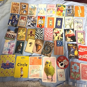 May include: A collection of various playing cards and collectible cards, including Disney characters, Dr. Seuss, and Coca-Cola designs. Some cards feature images of animals, flowers, and landmarks. The text "Yellow Circle" and "Brain Busters" are visible.