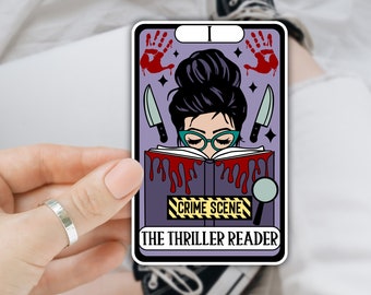 Op de afbeelding: Een paarse en witte sticker met een cartoonillustratie van een persoon die een boek leest met de tekst "Crime Scene" en "The Thriller Reader".