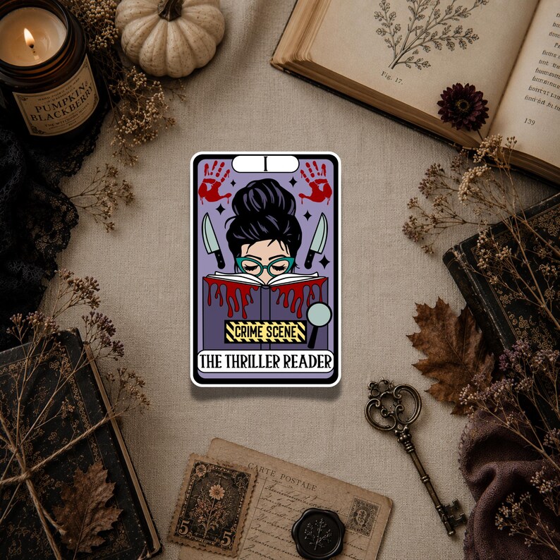 May include: A rectangular sticker featuring a purple tarot card design with a person reading a book. The illustration includes red handprints, two knives, a magnifying glass, and yellow caution tape with the text CRIME SCENE and THE THRILLER READER.