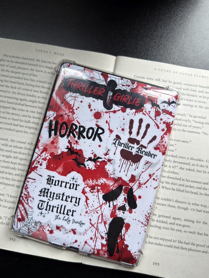 May include: A white and red horror-themed phone case with the words "Thriller Girlie", "Horror", "Thriller Reader", and "Horror Mystery Thriller" printed on it. The case has a blood splatter design and bat and handprint graphics.
