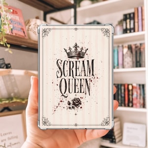 May include: A rectangular clear protective case for an electronic device featuring a cream-colored background with vertical stripes. The design includes a black crown, the text "SCREAM QUEEN" in a stylized font, a rose, and red paint splatters.