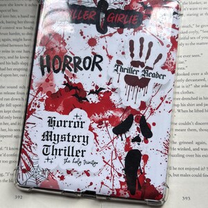 May include: A clear phone case with a horror theme. The case features a white background with red splatter designs and black bat silhouettes. Text includes "HORROR", "Thriller Reader", and "Horror Mystery Thriller".