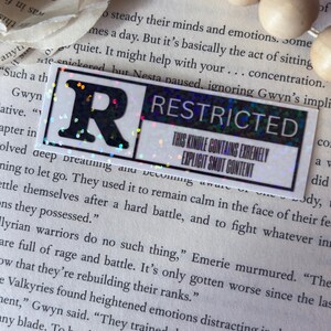 May include: A rectangular sticker with a black letter R on the left and the word RESTRICTED in black on the right. Below the word RESTRICTED, the text reads THIS KINDLE CONTAINS EXTREMELY EXPLICIT SMUT CONTENT. The sticker has a holographic finish.
