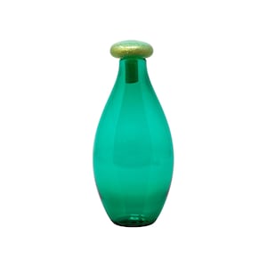 May include: A teal glass bottle with a gold-colored stopper. The bottle has a teardrop shape and a smooth, reflective surface. The stopper is round and has a textured, glittery appearance. The bottle is empty and stands upright.
