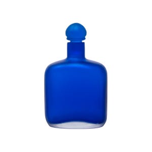 May include: A cobalt blue glass bottle with a rounded rectangular shape and a matching spherical stopper. The bottle has a frosted appearance, and the base is clear. The design is simple and elegant.
