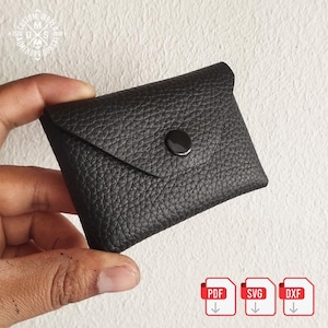 Op de afbeelding: Een kleine, zwarte leren portemonnee met een getextureerd oppervlak. De portemonnee heeft een klepsluiting die wordt vastgezet met een zwarte drukknop. De afbeelding bevat ook PDF-, SVG- en DXF-bestandspictogrammen.