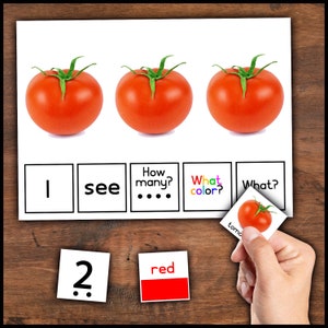 Pode incluir: Um cartão de aprendizagem com três tomates vermelhos, as palavras "Vejo", "Quantos?", "De que cor?" e "O quê?" com uma imagem de tomate. Abaixo do cartão, há três cartões com os números "2", "vermelho" and uma imagem de tomate.