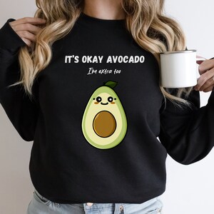 May include: Black sweatshirt with a white graphic of a smiling avocado and the text "It's okay avocado I'm extra too."
