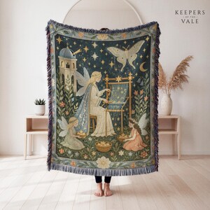 May include: A woven throw blanket featuring a dark blue night sky scene with stars, a crescent moon, and a large moth. The design depicts three winged figures, one weaving at a loom and two holding baskets of stars, set against a stone tower and flowers.