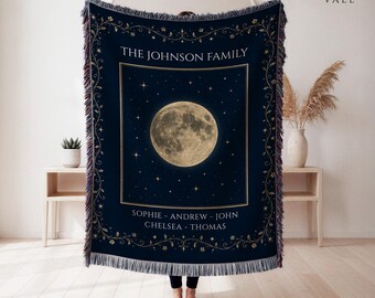 May include: A dark navy blue woven throw blanket featuring a large, detailed golden moon centered against a starry night sky. The text reads THE JOHNSON FAMILY and SOPHIE - ANDREW - JOHN CHELSEA - THOMAS. It has a decorative floral border and fringe.