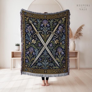 May include: A rectangular woven throw blanket featuring a dark blue background with a symmetrical pattern of two crossed swords, purple irises, and green foliage. The border has a gold and black decorative motif with fringe on the edges.