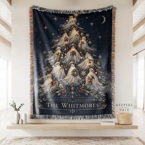 May include: A dark blue woven throw blanket featuring a Christmas tree composed of multiple white ghosts wearing Santa hats, holding lanterns and gifts. The text reads GHOSTS OF CHRISTMAS THE WHITMORES. The blanket has a fringed edge.