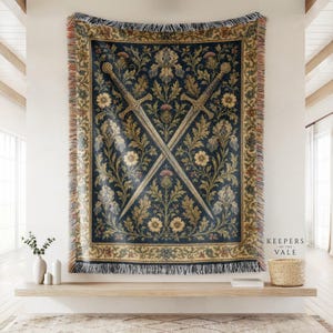 May include: A woven tapestry throw blanket featuring a dark blue background with a central design of two crossed swords surrounded by intricate floral and thistle patterns, finished with a decorative fringed border and the text Keepers of the Vale.