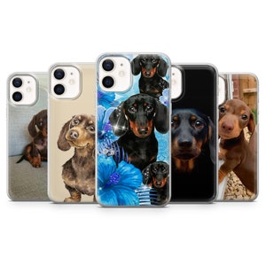 Könnte beinhalten: Fünf verschiedene iPhone-Hüllen mit Dackel-Motiven. Die Hüllen sind aus klarem Kunststoff mit verschiedenen Designs, darunter ein Aquarell-Dackel, ein Dackel mit blauen Blumen, ein schwarz-brauner Dackel, ein Dackel mit schwarzem Hintergrund und ein Dackel mit braunem Hintergrund.
