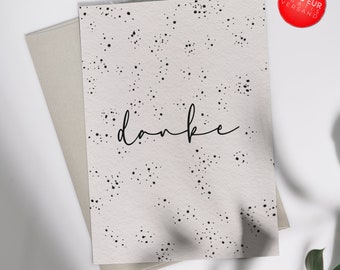 May include: A white card with a black polka dot pattern and the word "danke" written in black cursive. The card has a white border and the word "fili" written in black cursive at the bottom.