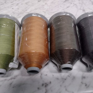 May include: Four spools of thread in different colors: green, orange, brown, and purple.