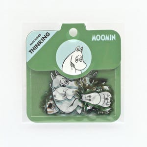 May include: A package of Moomin-themed stickers. The stickers feature various Moomin characters in black and white, with a green and white package. The package has the words "FACE SERIES" and "THINKING" printed on it.