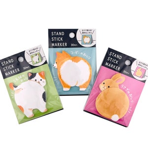 May include: Three packs of colorful sticky notes featuring the backsides of a cat, a corgi, and a rabbit. Each pack has 30 notes and says "Stand Stick Marker" in black text on a white background. The text "立てて使える! 便利なふせん" is also on each pack, which translates to "Stand up and use! Convenient sticky notes."