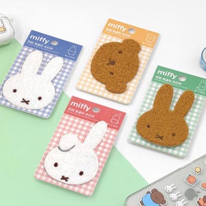Peut inclure: Quatre cartes colorées avec des patchs de lapin en fourrure. Chaque carte présente un lapin de couleur différente avec le texte "miffy" et du texte coréen sur le devant.