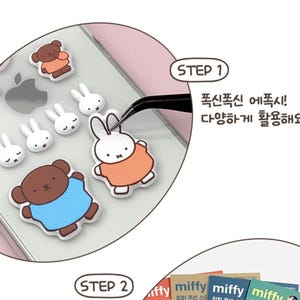 May include: A clear phone case with a variety of colorful stickers, including a brown bear wearing a blue shirt, a white bunny wearing an orange shirt, and several white bunnies with pink ears. The stickers are being applied to the phone case with tweezers. The text "STEP 1" and "폭신폭신 에폭시! 다양하게 활용해요." is visible in the image.