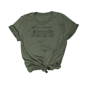 May include: A green t-shirt with a graphic of a desert landscape and the text "That by your grace I've been set free".