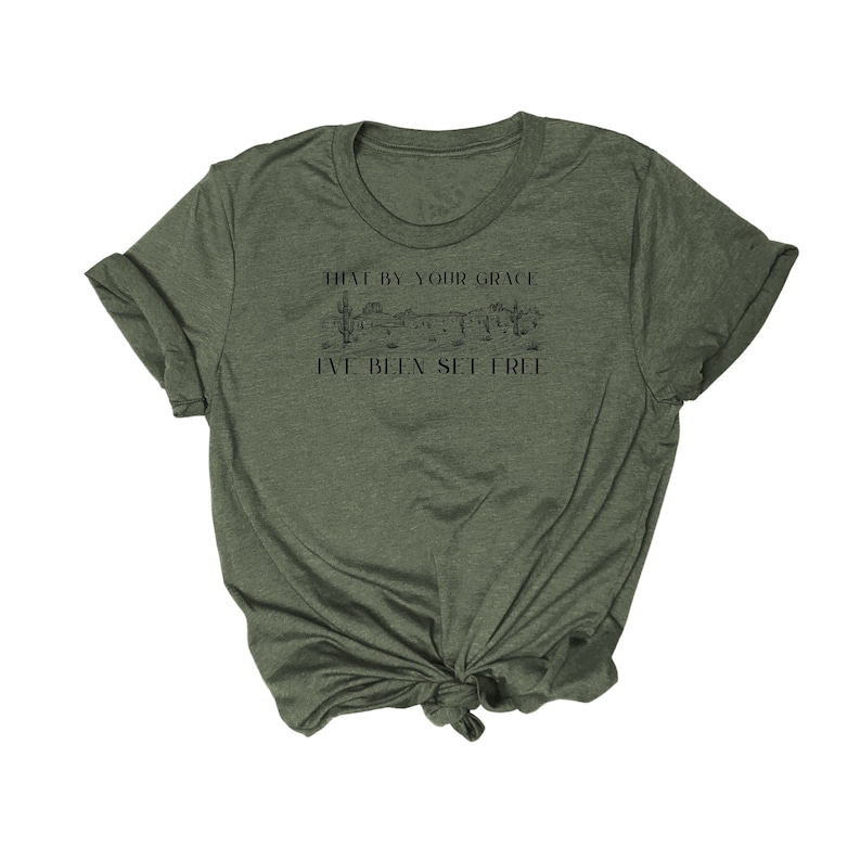 May include: A green t-shirt with a graphic of a desert landscape and the text "That by your grace I've been set free".
