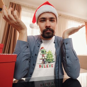 UFO Santa Alien saying Believe Unisex T-Shirt, Funny Alien Lover T-Shirt, UFO E.T. Holiday Gift Shirt, Graphic Alien Holiday Tee