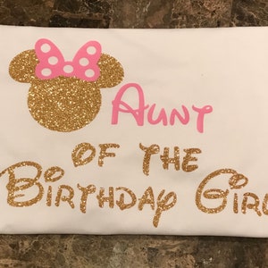 May include: White t-shirt with gold glitter Mickey Mouse ears and the text "Aunt of the Birthday Girl" in pink glitter.