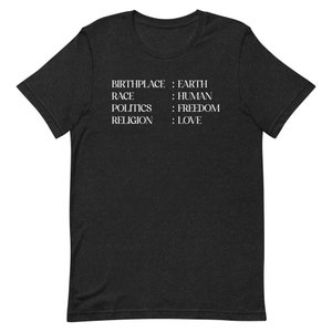 May include: A dark heather grey short-sleeved t-shirt featuring white text that reads: BIRTHPLACE : EARTH, RACE : HUMAN, POLITICS : FREEDOM, RELIGION : LOVE. The shirt has a crew neckline and a standard fit, displaying the printed text clearly on the chest.