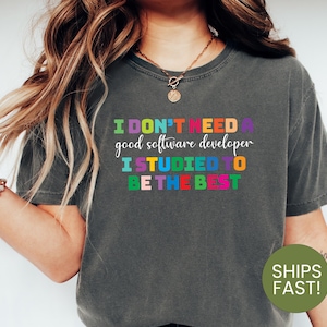 May include: A dark gray t-shirt with the text "I DON'T NEED A good software developer I STUDIED TO BE THE BEST" in colorful letters.