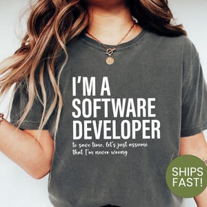 May include: A dark grey t-shirt with white text that reads "I'm a Software Developer to save time, let's just assume that I'm never wrong."