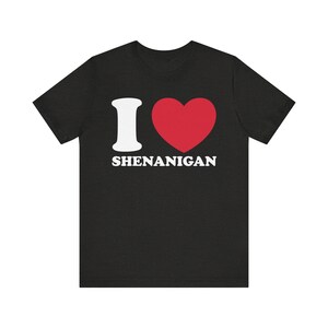 May include: Black t-shirt with a white "I love" graphic and a red heart. The text "Shenanigan" is printed below the heart.