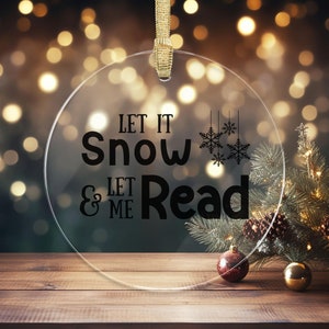 A clear acrylic Christmas ornament that says let it snow & let me read.