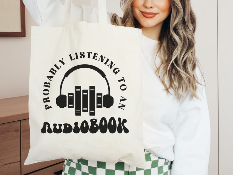 May include: White tote bag with black text that reads "Probably listening to an audiobook" with a graphic of headphones and books.