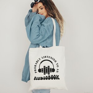 May include: White tote bag with black text that reads "Probably listening to an audiobook" with a graphic of headphones and books.