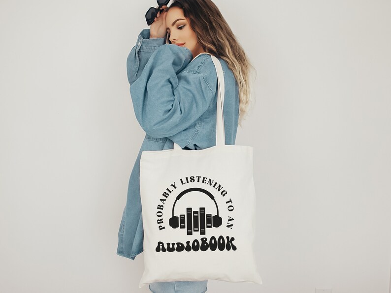 May include: White tote bag with black text that reads "Probably listening to an audiobook" with a graphic of headphones and books.