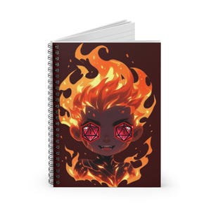 May include: A spiral-bound notebook featuring a graphic illustration of a character with flaming hair and twenty-sided dice for eyes. The character has dark skin, sharp teeth, and is surrounded by orange and yellow flames against a dark background.