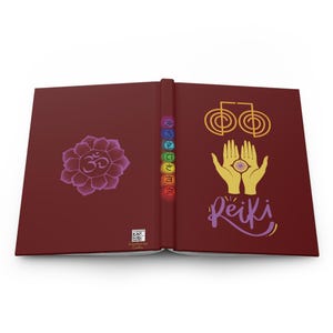 May include: A burgundy journal with a purple Om symbol on the front cover, a rainbow of chakra symbols on the spine, and a yellow Reiki symbol with two hands on the back cover.