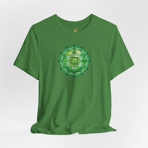 May include: Green t-shirt with a green and gold chakra symbol on the front. The symbol is a stylized flower with a Sanskrit symbol in the center.